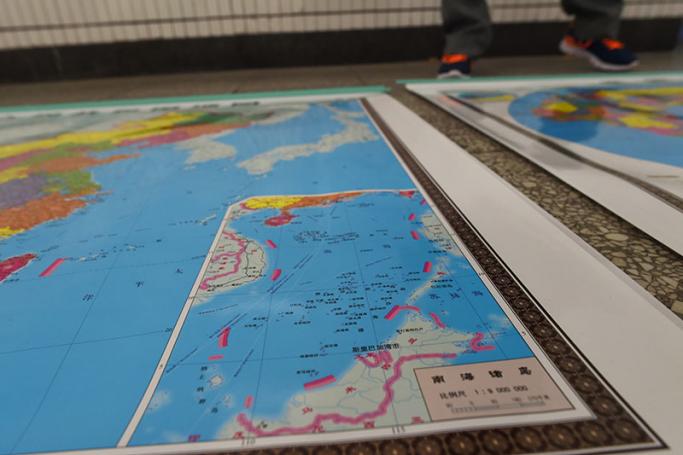 A vendor stands behind a map of China including an insert with red dotted lines showing China's claimed territory in the South China Sea, in Beijing. Photo: Greg Baker/AFP
