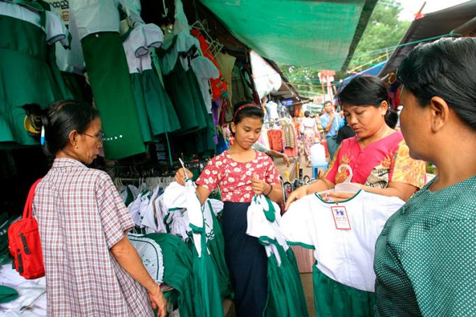 Women examine goods at one of the many roadside markets in the capital Yangon. Photo: EPA
