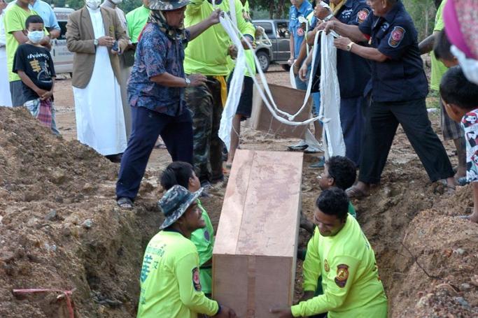 A photo made available on 04 May 2015 shows Thai rescue workers and Muslim villagers burying coffins containing the remains of suspected ethnic Rohingya migrants. Photo: EPA
