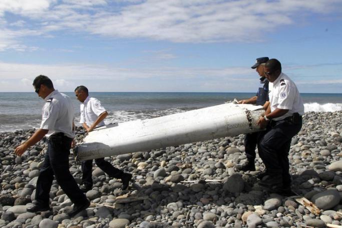 Parts of the missing airliner? Officers carrying pieces of debris from an unidentified aircraft apparently washed ashore in Saint-Andre de la Reunion, eastern La Reunion island. Photo: EPA
