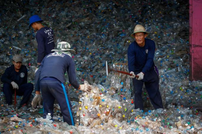 Migrant workers break apart blocks of pressed plastic bottles at the Thaiplastic Recycle Group plant in Samut Sakhon, outside Bangkok, Thailand. Photo: Diego Azubel/EPA