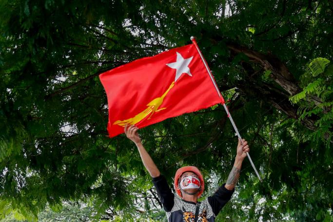 (File) A man raises the flag of National League for Democracy (NLD) party over his head during an election campaign rally in Yangon, Myanmar, 18 October 2020. Photo: EPA