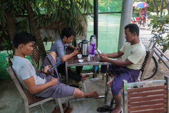 Myanmar men using their mobile phones at a teashop in Yangon. Photo: AFP