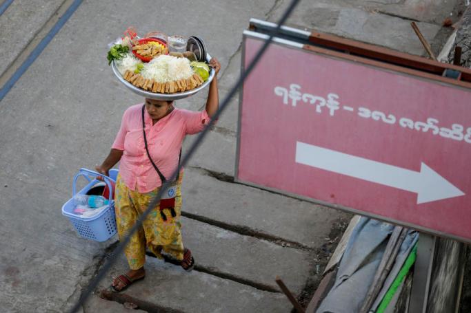 A street vendor carries food on her head to sell around downtown Yangon, Myanmar, 16 November 2020. Photo: Lynn Bo Bo/EPA