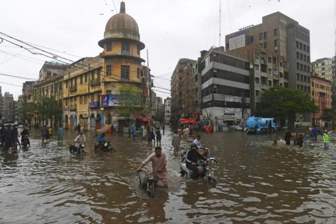 People wade across a flooded street after heavy monsoon rainfall in Karachi on July 25, 2022. Photo: AFP