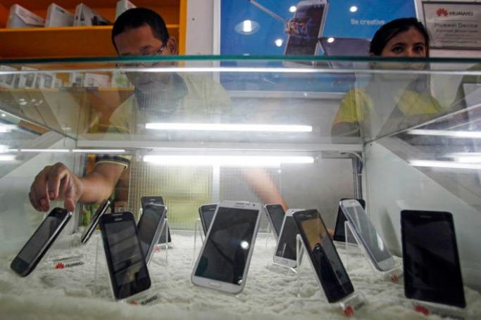 Employees work behind the mobile phone handsets displayed at a mobile phone shop in Yangon, Myanmar, June 28, 2013. Photo: Lynn Bo Bo/EPA
