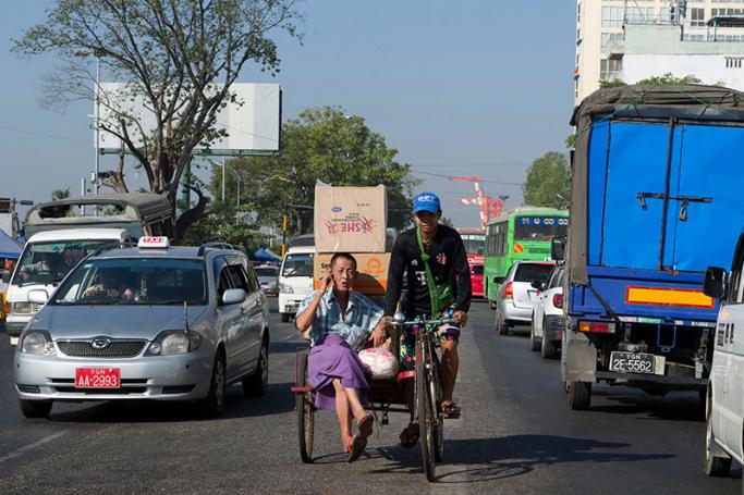 A man using a mobile phone transports his goods in a trishaw in central Yangon's busy Strand Road on December 14, 2016. Photo: Romeo Gacad/AFP
