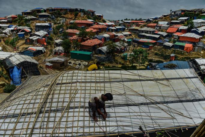 A Rohingya refugee uses bamboo to fix his roof during the monsoon season at Balukhali refugee camp in Ukhia on July 21, 2018. Photo: Munir Uz Zaman/AFP
