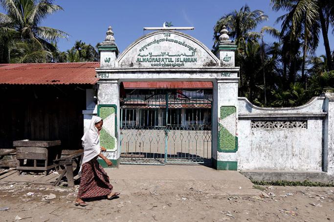 A Muslim woman walks by in front of the local mosque in the Aung Mingalar quarter in Sittwe, Myanmar. Photo: Nyein Chan Naing/EPA
