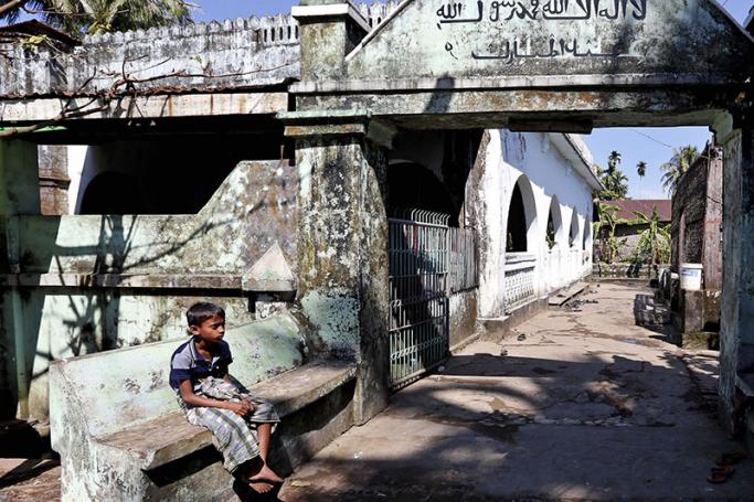 A Muslim boy sits in front of the local mosque in the Aung Mingalar quarter in Sittwe, western Myanmar. Photo: Nyein Chan Naing/EPA
