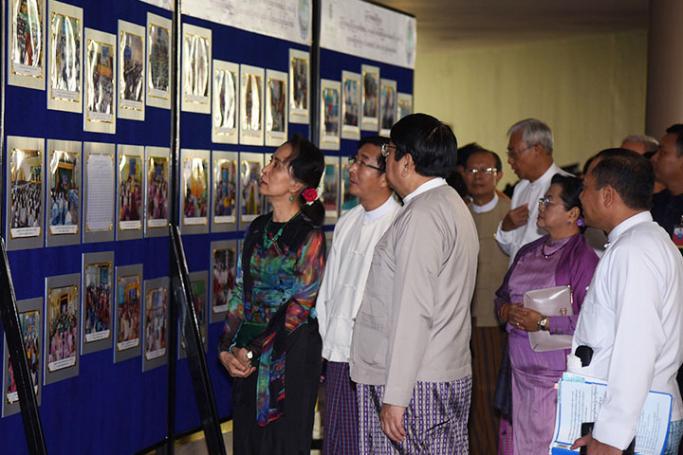 State Counsellor Daw Aung San Suu Kyi, former President U Htin Kyaw and wife, and dignitaries looking at documentary photos on activities of community centres displayed at the ceremony to hand over mobile libraries of Daw Khin Kyi Foundation to Ministry of Information in Nay Pyi Taw yesterday. Photo: MNA