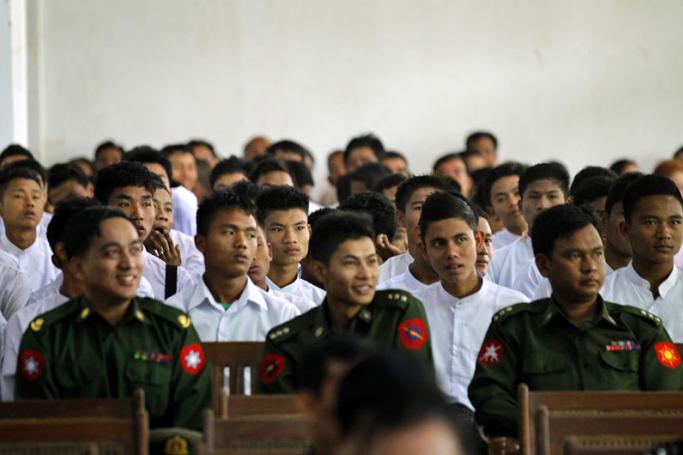 Boys wearing white shirts, released from the Myanmar army, sit behind military officers during a ceremony to handover discharged minors in Yangon, Myanmar, 18 January 2014. Photo: Lynn Bo Bo/EPA
