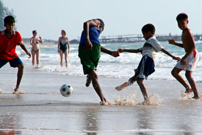 Myanmar children play soccer as foreign tourists stroll along the waters edge on Ngapali beach, on the Bay of Bengal, west coast of Myanmar. Photo: Gernot Hensel/EPA
