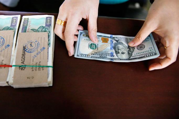 A money changer handles a transaction of US dollar and Myanmar Kyats. Photo: EPA