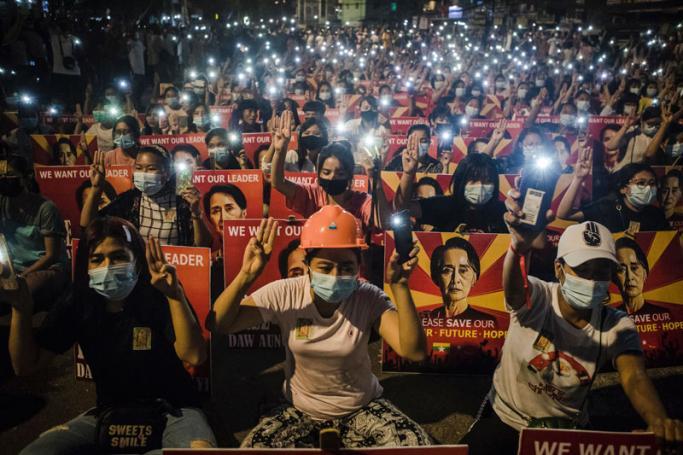 Protesters hold up the three finger salute and placards with the image of detained Myanmar civilian leader Aung San Suu Kyi while using their mobile torches during a demonstration against the military coup in Yangon. Photo: AFP