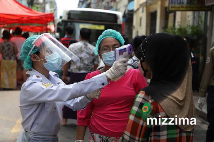 A medical staff member wearing protective gear takes the temperature of a resident while going door-to-door for health check-ups in Yangon on May 22, 2020. Photo: Thet Ko/Mizzima