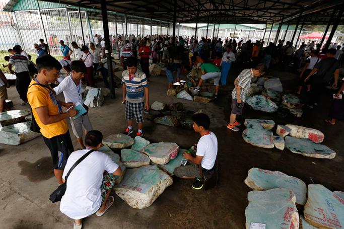 Buyers examine Jade stones on sale displayed at the 53rd Myanmar Gems Emporium in Naypyitaw, Myanmar, 24 June 2016. Photo: Hein Htet/EPA
