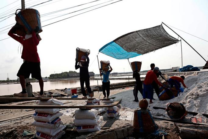 Myanmar migrant labourers carrying baskets of salt to load into a truck after the harvest at a salt farm in Samut Sakhon province, Thailand, 05 April 2016. Photo: Rungroj Yongrit/EPA
