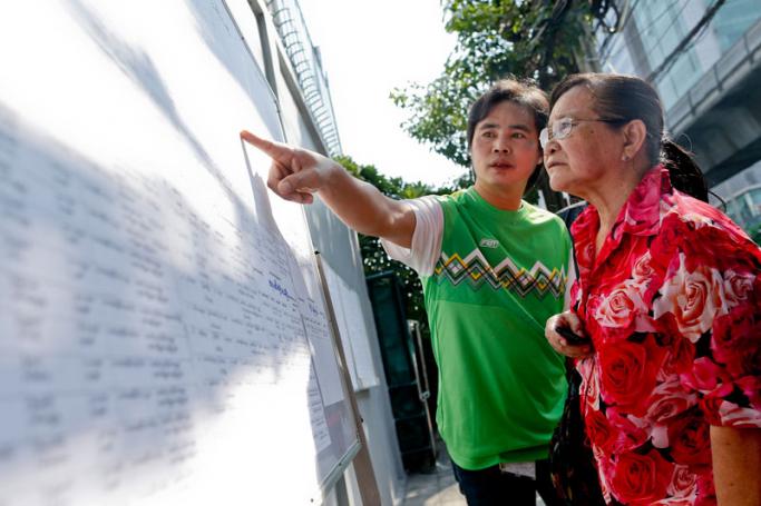 Myanmar nationals search for their names on lists outside the Myanmar Embassy as they wait for their turn to vote early, in Bangkok, Thailand, 17 October 2015. Photo: Diego Azubel/EPA
