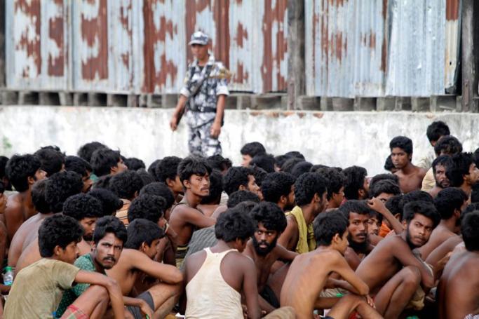 A policeman stands guard as migrant people rescued by the Myanmar Navy at sea, arrive to Kayin Chaung Jetty near MaungDaw township, Rakhine State, western Myanmar, 03 June 2015. Photo: Nyunt Win/EPA
