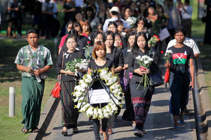 People carry a wreath and flowers as they walk during prayers for the deaths of two Kachin ethnic school teachers, in Yangon, Myanmar, 23 December 2014. Photo: Lynn Bo Bo/EPA
