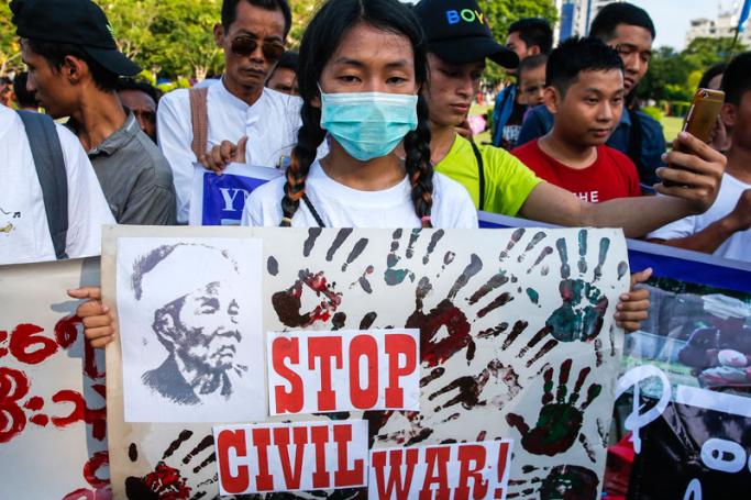 A girl wearing mask holds a placard during the demonstration against the recent clashes at Kachin State in northern Myanmar, in Yangon, Myanmar, 06 May 2018. Photo: Lynn Bo Bo/EPA-EFE
