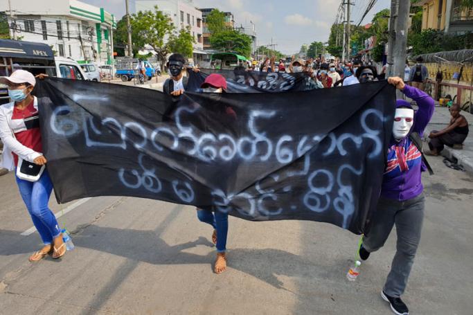 Protesters hold banners during a demonstration against the military coup in Yangon's Insein township on May 1, 2021. Photo: AFP