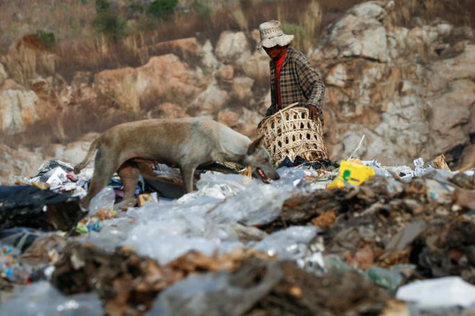 A dog searches for food as a man scavenges through rubbish to try and sell to recyclers, at a giant garbage dump on the outskirts of the capital, Naypyitaw. Photo: Lynn Bo Bo/EPA