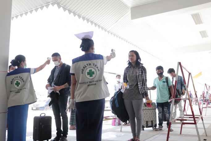 People have their temperatures checked amid concerns over the spread of the COVID-19 coronavirus at the immigration post in Myawaddy near the Thai border on March 23, 2020, as thousands of people crossed from Thailand as the border crossings were due to close because of the growing pandemic. Photo: AFP