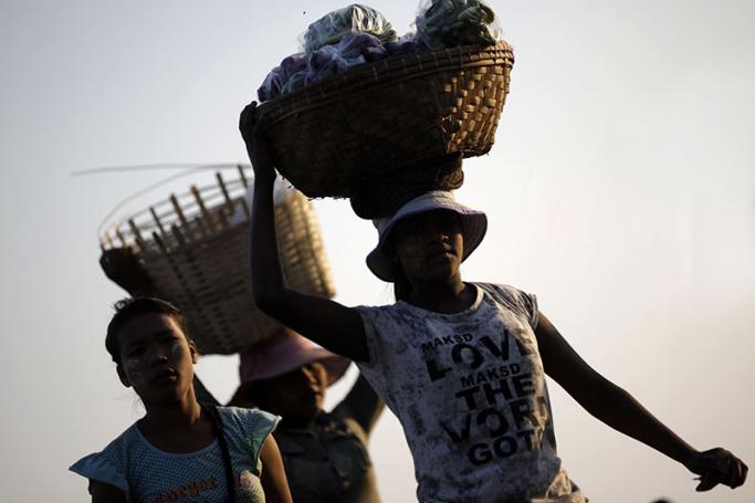 Myanmar women carry baskets loaded with fruit to sell. Photo: Lynn Bo Bo/EPA
