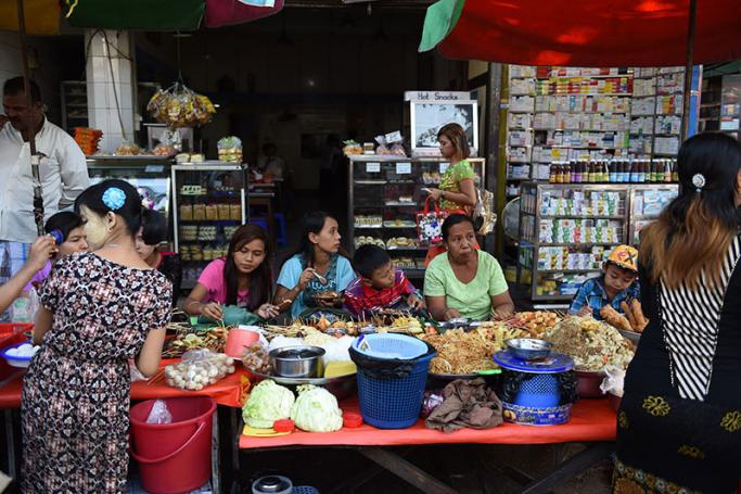 Myanmar women and children eat their meal on a sidewalk stall in Yangon. Photo: Romeo Gacad/AFP
