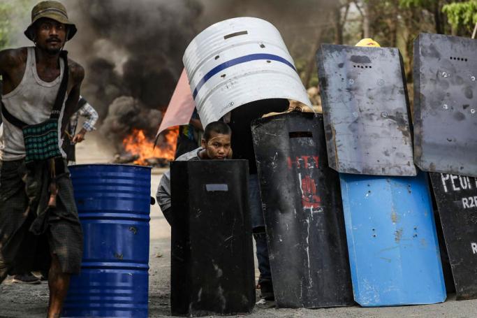 Demonstrators takes cover behind metal shields during a protest against the military coup in Hlaingthaya (Hlaing Tharyar) Township, outskirts of Yangon, Myanmar, 14 March 2021. Photo: EPA