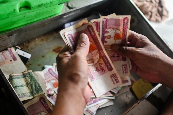 A shopkeeper counts the Myanmar kyat currency at his shop in Yangon. Photo: AFP