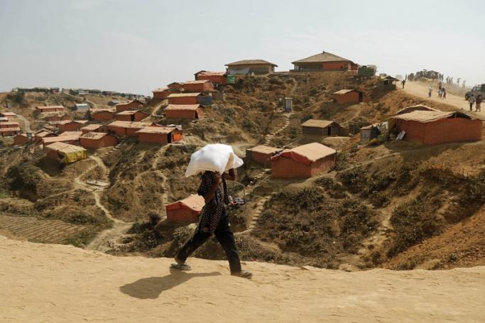 A Rohingya refugee returns to camp carrying relief goods at the site of the newly extended refugee camps at Kutupalong in UKhiya, Cox's Bazar, Bangladesh, 12 February 2018. Photo: Abir Abdullah/EPA-EFE
