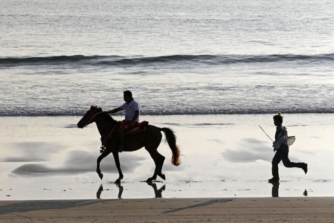 Guest riding a horse as horse owner follow on the NgweSaung Beach, also called Silver Sands, near Ngwe Saung township, some 260 km from Yangon in Pathein province, Ayeyarwaddy Devision, Myanmar. Photo: Nyein Chan Naing/EPA
