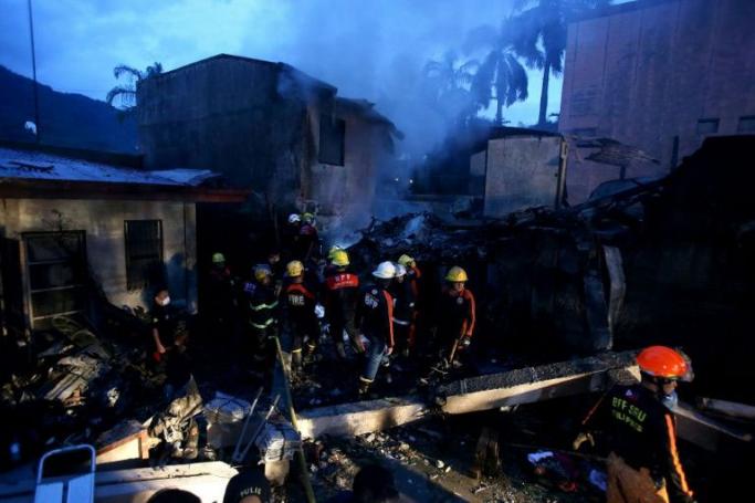 Firefighters sift through the site where an air-ambulance plane crashed as they search for the bodies of passengers, at a resort area in Calamba City, Laguna province, south of Manila on September 1, 2019. Photo: AFP