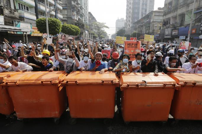 Demonstrators stand behind a barrier of waste containers as they face riot police during a protest against the military coup, in Yangon, Myanmar, 28 February 2021. Photo: EPA