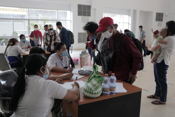 (File) Myanmar nationals wearing facemasks amid concerns over the spread of the COVID-19 coronavirus speak with officials at the immigration post in Myawaddy near the Thai border on March 23, 2020, as thousands of people crossed from Thailand as the border crossings were due to close because of the growing pandemic. Photo: AFP