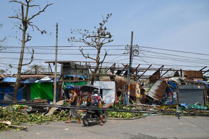 People pass damaged structures in Sittwe in Myanmar's Rakhine state on May 15, 2023, after cyclone Mocha made landfall. Photo: AFP