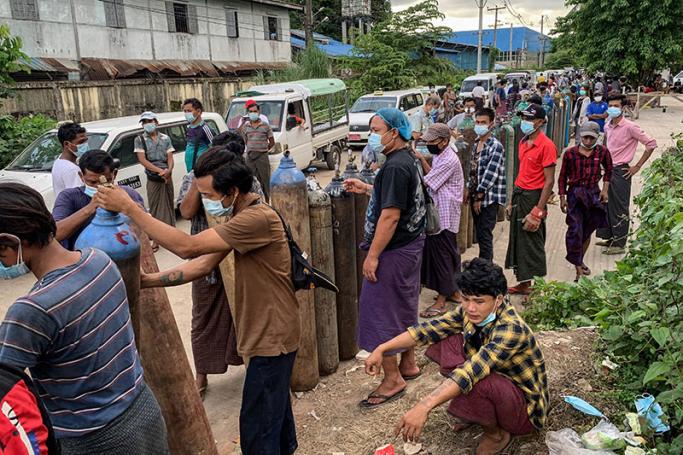 This picture taken on July 14, 2021 shows people waiting to fill up empty oxygen canisters outside a factory in Yangon, amid a surge in the number of Covid-19 coronavirus cases. Photo: AFP