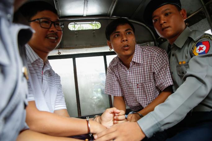 Reuters journalist Wa Lone (C-L), 31, and Kyaw Soe Oo (C-R), 28, sit in the police truck as they leave the court after the verdict has postponed at Insein township court, Yangon, Myanmar, 27 August 2018. Photo: Lynn Bo Bo/EPA