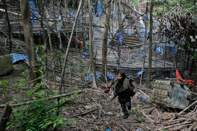 An armed Royal Malaysia Police Officer in front of an abandoned camp near graves found at Wang Burma hills at Wang Kelian, Perlis in Malaysia, 26 May 2015. Photo: Fazry Ismail/EPA
