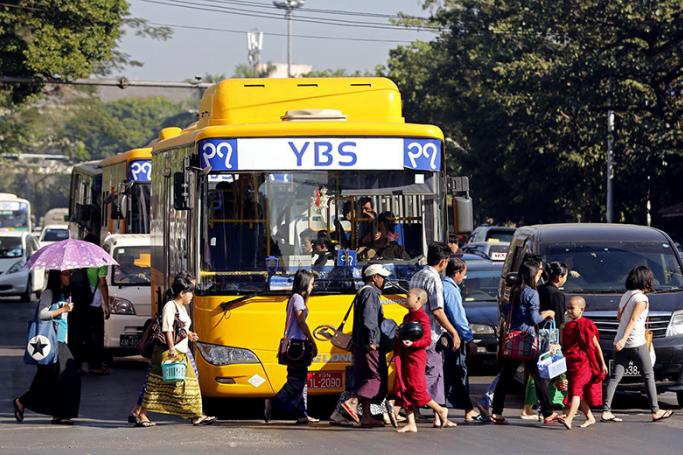 People walk in front of a YBS bus at a traffic light during rush hour in Yangon. Photo: Nyein Chan Naing/EPA
