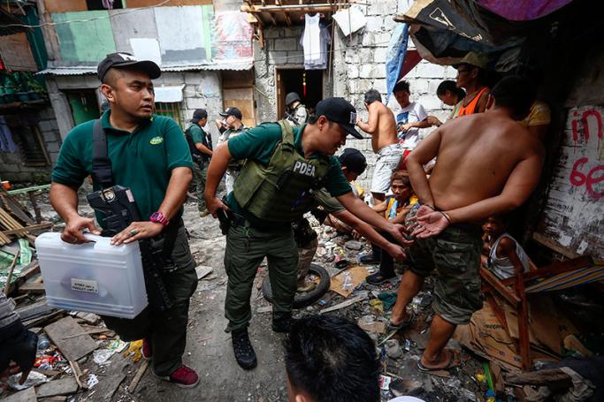 A lead operative (C) of the Philippine Drug Enforcement Agency (PDEA) searches the pockets of a man (R) suspected of involvement in illegal drugs during a raid in a residential district of Pasig City, east of Manila, Philippines 13 February 2017. Photo: Rolex Dela Pena/EPA

