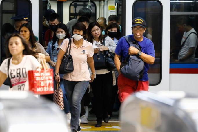 Passengers wearing protective masks disembark from a car at a terminal of the Metro Rail Transit in Quezon City, Philippines, 10 March 2020. Photo: EPA
