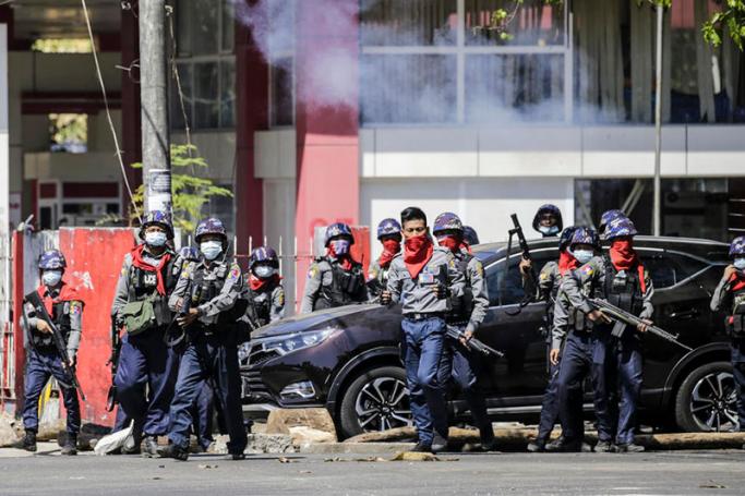 Anti-riot police officers prepare to fire tear gas as they try to disperse protesters during an anti-coup protest following the military crackdown in Yangon. Photo: EPA