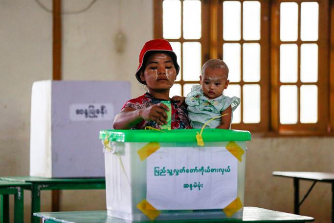 A woman carries her child as she casts her vote for by-elections at a polling station of Hlaing Thar Yar township in Yangon, Myanmar, 01 April 2017. Photo: Lynn Bo Bo/EPA
