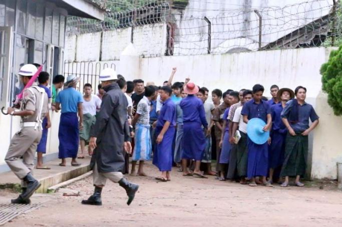 Prison officials pass by a group of inmates waiting to be taken to their cells in Yangon's Insein Prison. Photo: Swe Win / Myanmar Now
