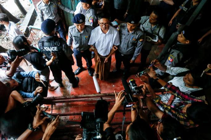 Detained Reuters journalist Wa Lone (C) talks to media as he is escorted by police after his trial at the court in Yangon, Myanmar, 23 July 2018. Photo: Lynn Bo Bo/EPA
