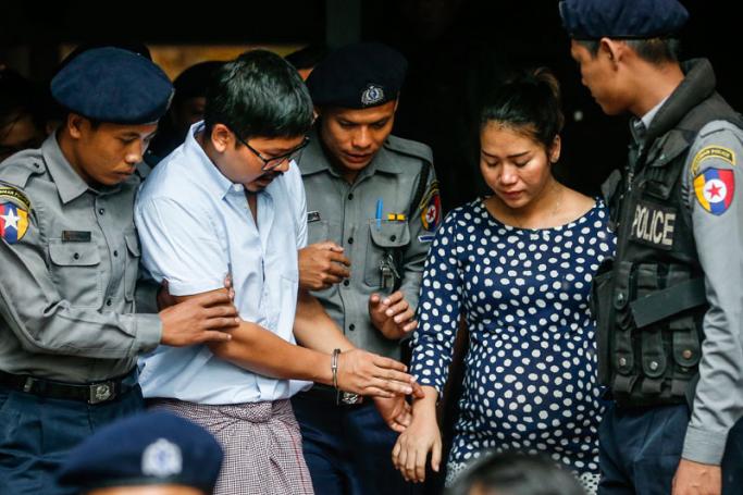 Detained Reuters journalist Wa Lone (2-L) is escorted out of court by police as he lets go of his pregnat wifes (2-R) hand after a trial at the court in Yangon, Myanmar, 09 July 2018. Photo: Lynn Bo Bo/EPA

